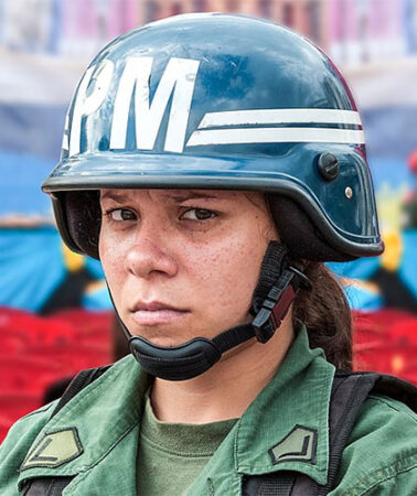 A female soldier looks uneasily into the camera at a political event in Caracas