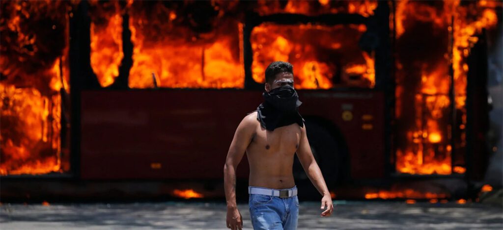 A protester walks in front of a burning bus in Caracas, Venezuela